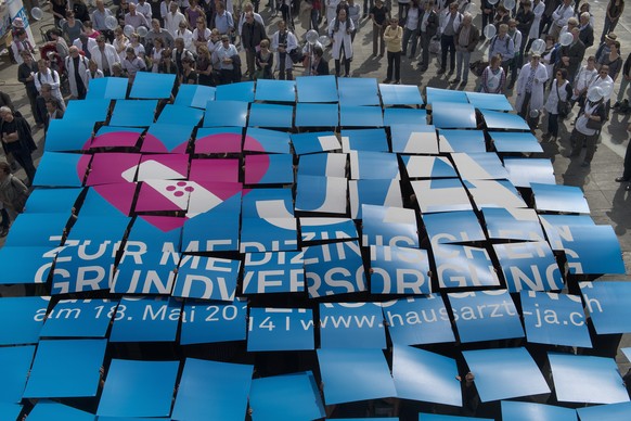 Hausaerztinnen und Hausaerzte werben mit einer Plakataktion fuer die Hausarztmedizin am Dienstag, 1. April 2014 auf dem Bundesplatz in Bern. Die Volksabstimmung ueber den &quot;Bundesbeschluss ueber d ...