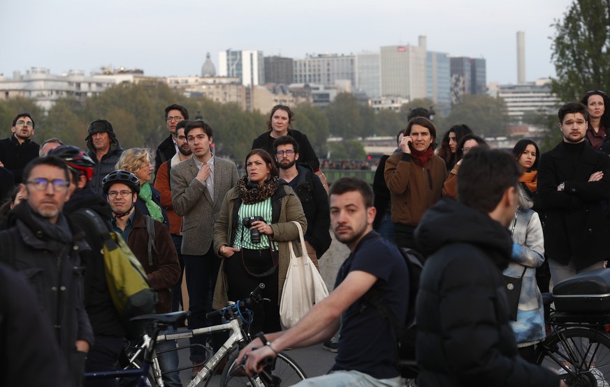 People watch as flames and smoke rise from Notre Dame cathedral as it burns in Paris, Monday, April 15, 2019. Massive plumes of yellow brown smoke is filling the air above Notre Dame Cathedral and ash ...