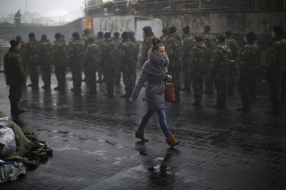 Unabhängigkeitsplatz in Kiew: Eine junge Frau überquert den Platz, während ukrainische Rekruten exerzieren. 