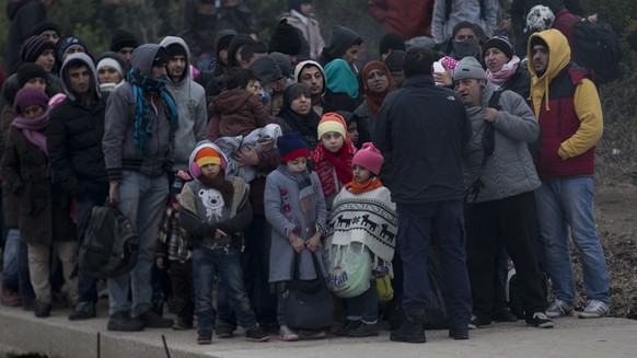 In this photo taken on Wednesday, Jan. 20, 2016, a Greek coast guard officer gives instructions to refugees and migrants who are traveling from the deserted Greek island of Pasas to Oinousses island b ...