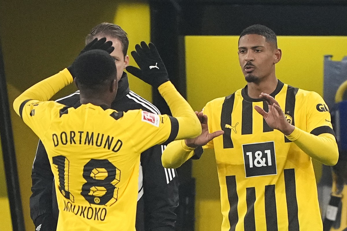 Dortmund's Sebastien Haller, right, high fives with Dortmund's Youssoufa Moukoko when entering the pitch as substitute player during the German Bundesliga soccer match between Borussia Dortm ...