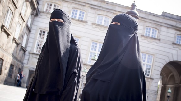 epa06775145 Women wearing the niqab walk in front of the Danish Parliament at Christiansborg Castle in Copenhagen, Denmark, 31 May 2018. A majority in the Danish Parliament adopted a ban wearing niqab ...