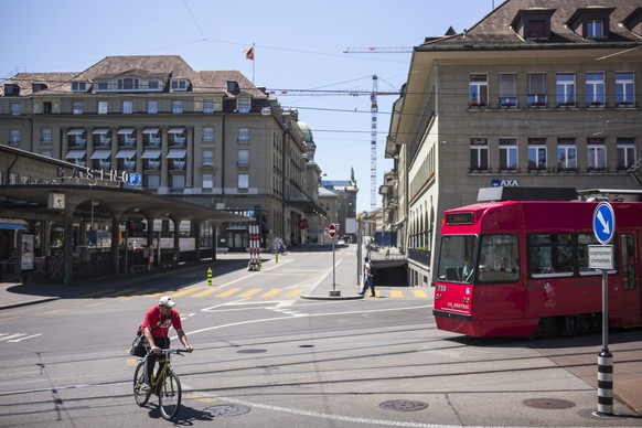 Ein Velofahrer kreuzt ein Tram der Linie 7 am Casinoplatz in Bern, im Hintergrund das Hotel Bellevue und das Bundeshaus, am Sonntag, 28. Juni 2015. (KEYSTONE/Alessandro della Valle)