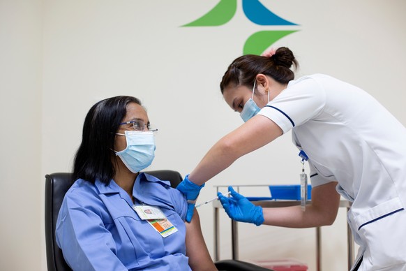 epa08900980 A handout photo made available by the Dubai Government of Media Office shows a nurse (L) from Dubai Health Authority (DHA) receiving the first dose of the Pfizer-BioNTech COVID-19 vaccine  ...