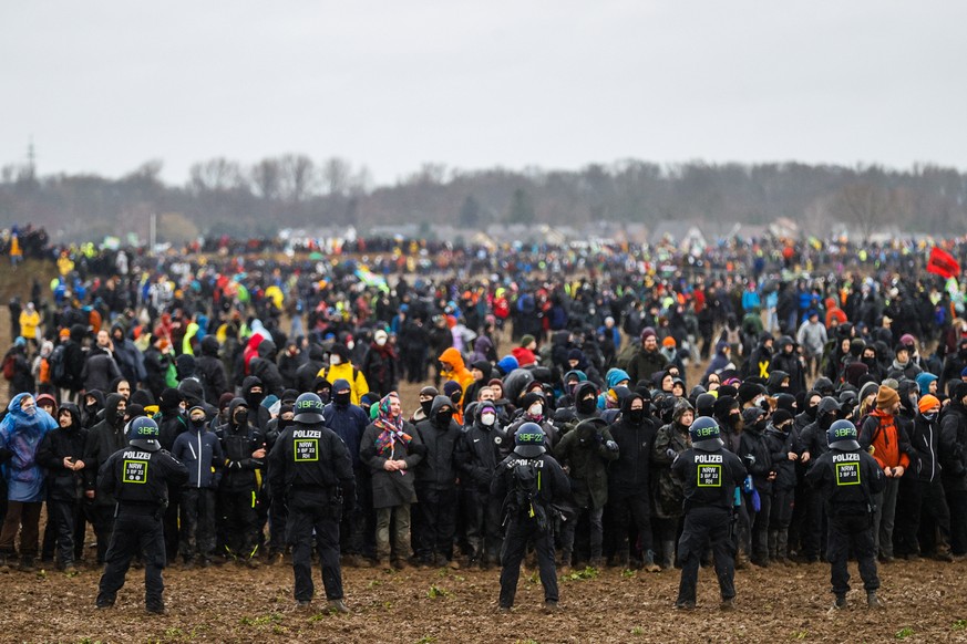 epa10405143 Police officers stand in front of protesters during a rally of climate protection activists near the village of Luetzerath, Germany, 14 January 2023. Luetzerath in North Rhine-Westphalia s ...