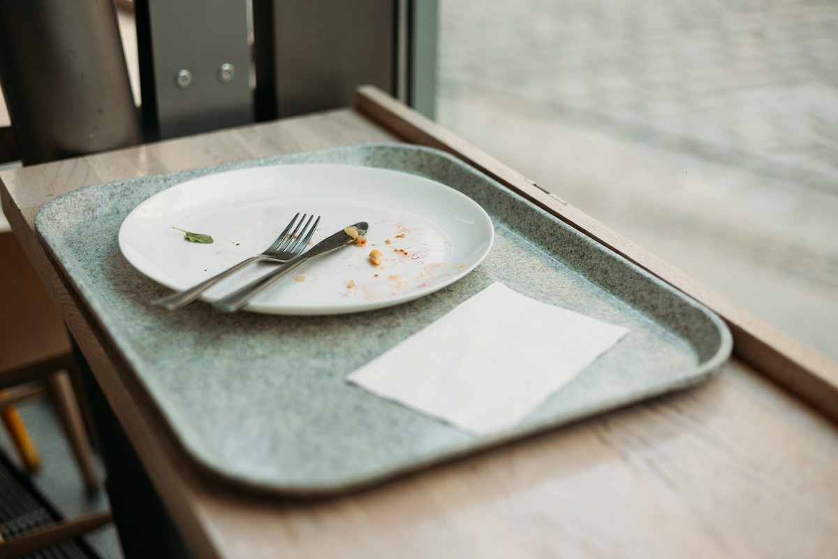 lunch tray with Empty dirty dish. White plate with fork and knife on table