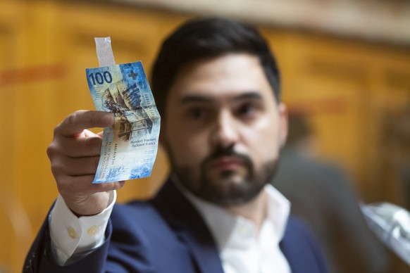 Cedric Wermuth, Nationalrat SP-AG, nimmt eine 100 Franken Banknote weg, die er waehrend seiner Rede an die Plexiglasscheibe geklebt hat, waehrend der Debatte um die Volksinitiative &quot;Loehne entlas ...