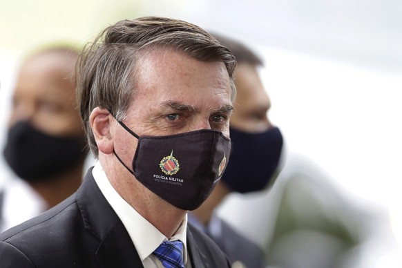 FILE - In this May 18, 2020, file photo, Brazilian President Jair Bolsonaro wears a mask due to the coronavirus pandemic as he talks with supporters upon departure from his official residence, Alvorad ...