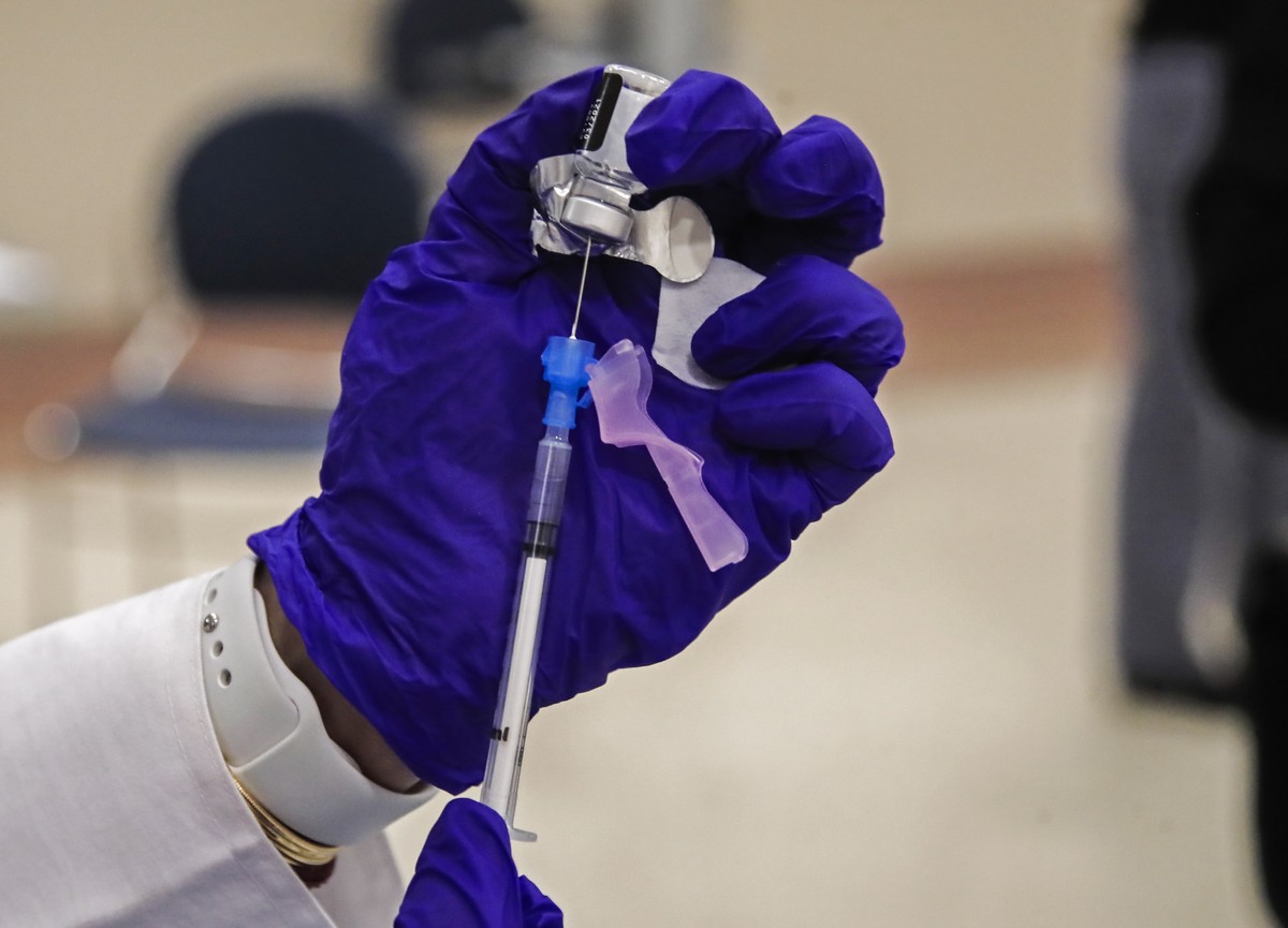 epa08890835 Registered Nurse Elsa Methipara prepares the Pfizer-BioNTech COVID-19 vaccine for Dr. Emanuel Ogele to receive his inoculation at the Cook County Health Department in Chicago, Illinois, US ...