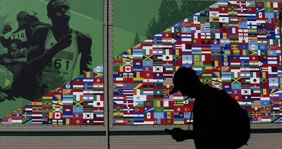A pedestrian strolls past a poster on the outside of Hayward Field in Eugene, Ore., on Thursday, April 16, 2015, depicting international athletes and national flags. The poster was used for the IAAF W ...