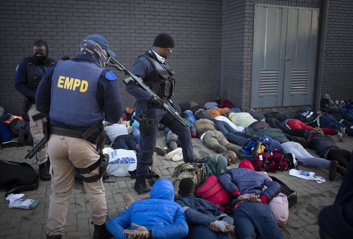 epa09341813 Police and security guards stand over arrested looters in Johannesburg, South Africa, 13 July 2021. Former South Africa President Zuma was arrested on 07 July, and sentenced to 15 months i ...