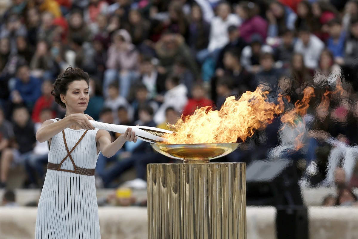 epa06299354 Greek actress Katerina Lechou, in the role of the High Priestess, lights a torch with the Olympic flame during the handover ceremony of the Olympic flame at the Panathenaic Stadium, in Ath ...