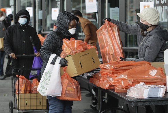 A Food Bank for New York City volunteer hands out packages at a mobile food pantry at Barclays Center Friday, April 24, 2020, in the Brooklyn borough of New York. (AP Photo/Frank Franklin II)