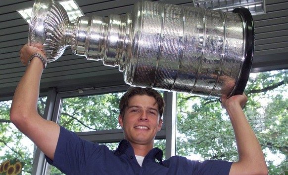 Swiss Ice-Hockey goalie David Aebischer lifts the Stanley Cup he won with his team Colorado Avalanche, Friday, August 31, 2001 in a car dealer's garage in Fribourg, Switzerland. Aebischer is the first ...