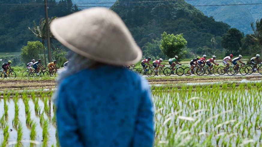 Cyclists compete as a villager looks on during the stage 5 of Tour de Singkarak 2014 from Payakumbuh City to Singkarak Lake with a distance of 102 km in West Sumatera province, Indonesia, June 11, 201 ...