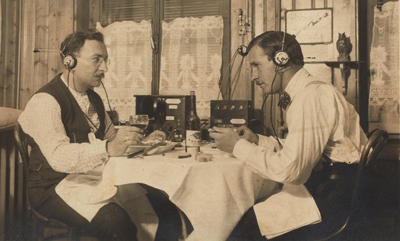 Zwei Radiohörer bei Speis und Trank in Sirnach. Aufnahme ca. 1923-1928. Quelle: Ansichtskarte, Fotograf Jean Mäder, Hub bei Sirnach, Museum für Kommunikation.