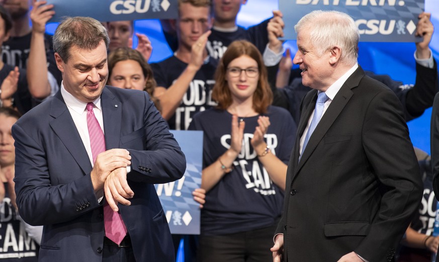 epa07022068 Bavarian Prime Minister Minister Markus Soeder (L) of the German Christian Social Union (CSU) looks at his watch next to German Minister of Interior, Construction and Homeland, chairman of ...