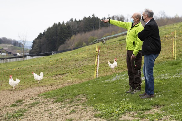 Bundespraesident Guy Parmelin, rechts, und Betriebsleiter Paul Messerli schauen sich das Gehege der Freilandhuehner an, wahrend einem Besuch auf dem landwirtschaftlichen Biobetrieb Messerli, am Montag ...