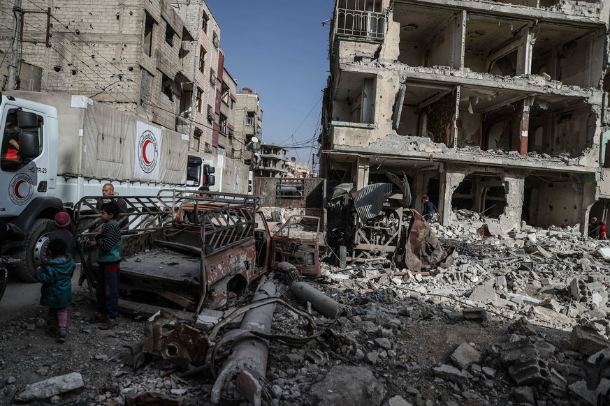 epa06583597 People walk along a convoy of Syrian Arab Red Crescent (SARC) trucks as they arrive in Douma, in Eastern Ghouta, Syria, 05 March 2018. Aid supplies reach the besieged community in Eastern  ...