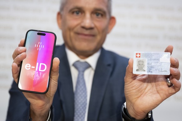 Bundesrat Beat Jans, posiert und haelt ein Handy mit der Aufschrift e-ID sowie seine Identitaetskarte in den Haenden, nach einer Medienkonferenz im Hinblick auf die Volksabstimmung vom 28. September 2 ...