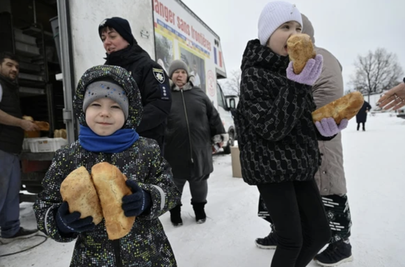 Kinder gehen mit zwei frischen Brotlaiben nach Hause.