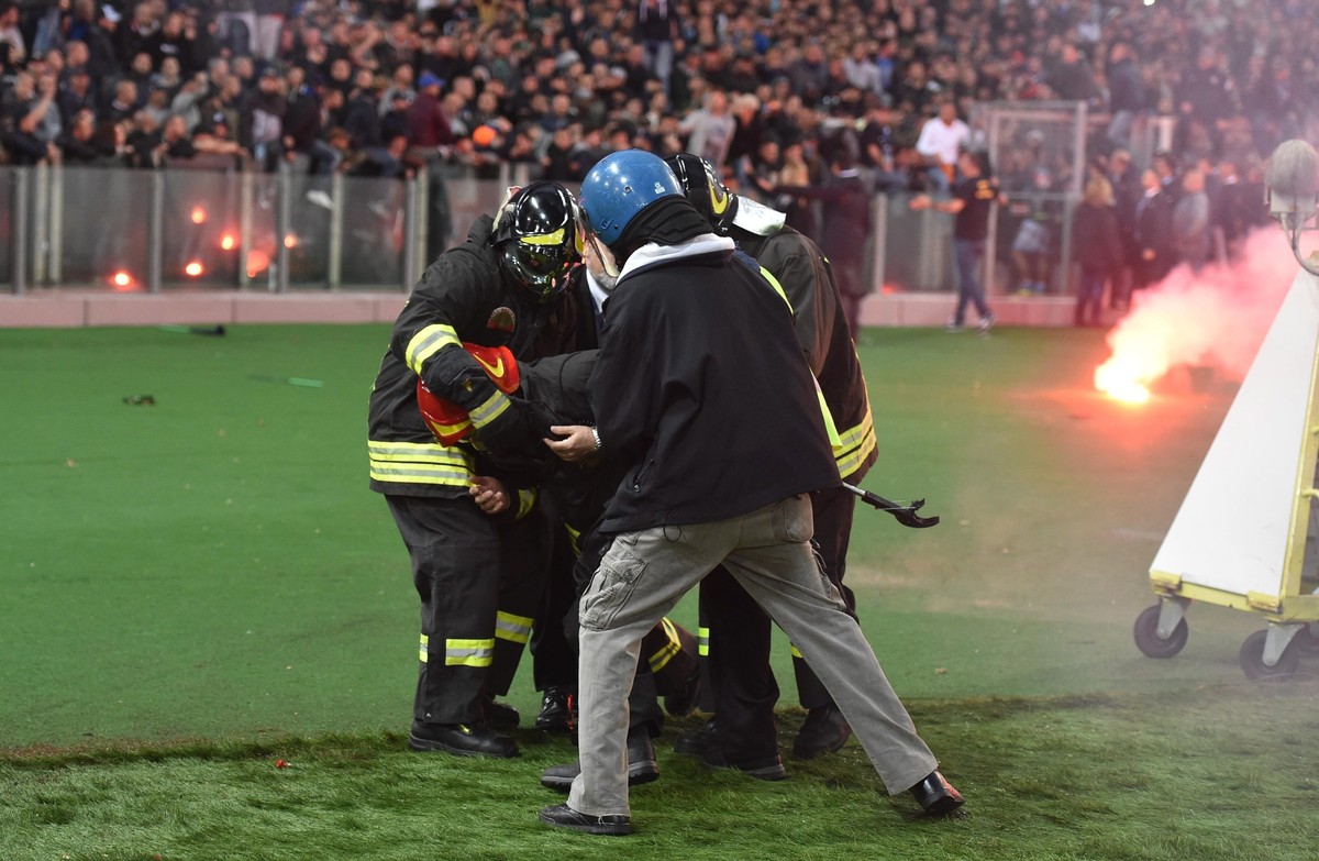 Eine dieser Petarden trifft einen Feuerwehrmann, der aus der Gefahrenzone getragen werden muss.