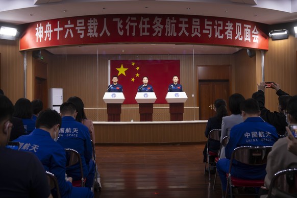 Chinese astronauts for the upcoming Shenzhou-16 mission, from left, Gui Haichao, Jing Haipeng, and Zhu Yangzhu stand behind glass during a meeting with the press at the Jiuquan Satellite Launch Center ...