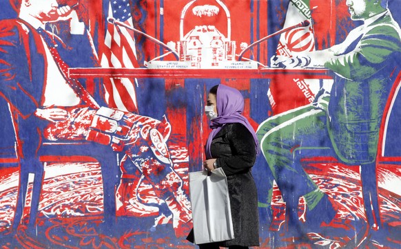 epaselect epa09707598 An Iranian woman walks past an anti-US wall painting on the wall of former US embassy in the capital city of Tehran, Iran, 25 January 2022. Iranian foreign minister Hossein Amir- ...