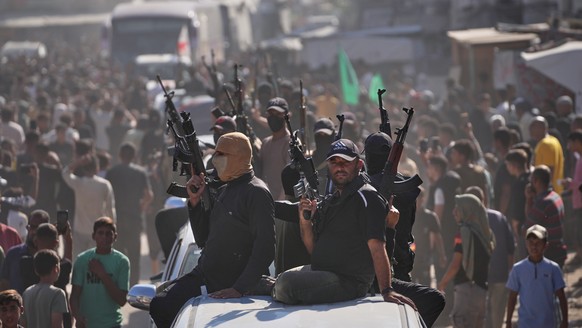 Hamas gunmen on pickup trucks escort buses carrying freed Palestinian prisoners as they are greeted following their release from Israeli jails under a cease-fire agreement between Hamas and Israel, in ...