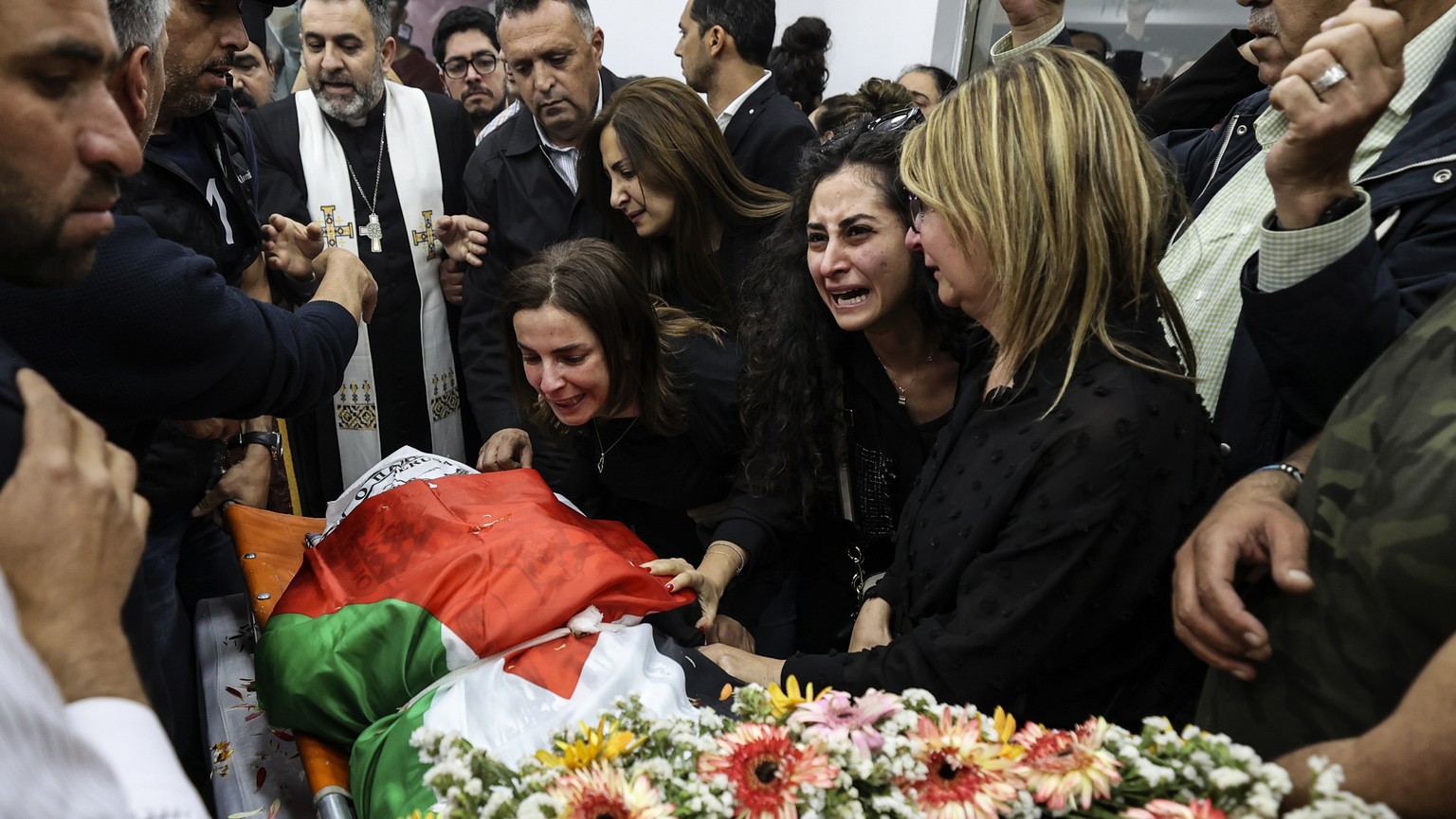 Colleagues and friends react as the Palestinian flag-draped body of veteran Al-Jazeera journalist Shireen Abu Akleh is brought to the offices of the news channel&#039;s office in the West Bank city of ...