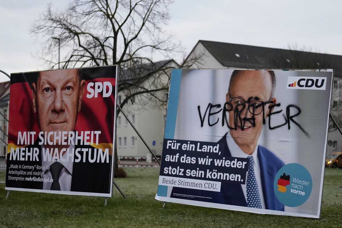 A defaced election poster for the Christian Democratic Union (CDU) with top candidate Friedrich Merz, right, that reads 'Traitor' is displayed beside a poster of German Chancellor Olaf Schol ...