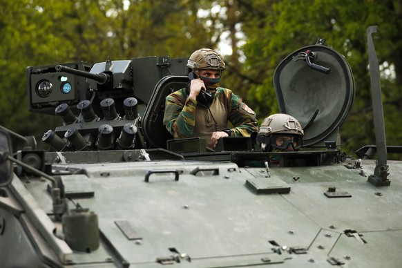 Belgian military sit in a tank at the entrance of the National Park Hoge Kempen in Maasmechelen, Belgium, Friday, May 21, 2021. Specialized forces on Friday continued their manhunt for an armed soldie ...