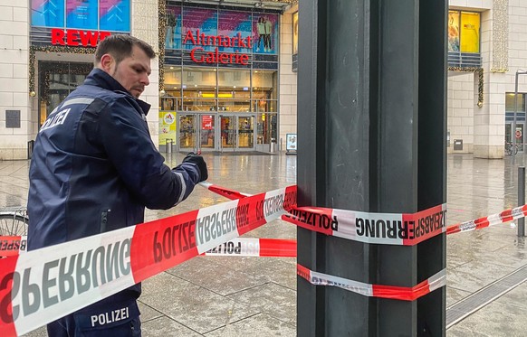 epa10358740 A police officer secures the area with a cordon in front of a shopping center in Dresden, Germany, 10 December 2022. Police evacuated a shopping mall and its surroundings in the center of  ...