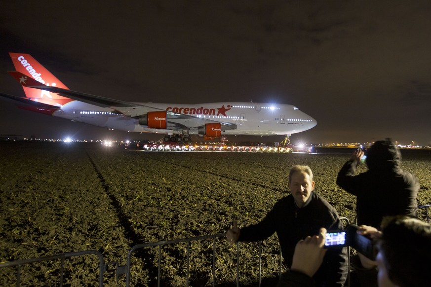 People pose for a picture as a self-propelled trailer transports a Boeing 747-400 plane through farmland from Schiphol Airport to a nearby hotel in Badhoevedorp, near Amsterdam, Netherlands, Wednesday ...