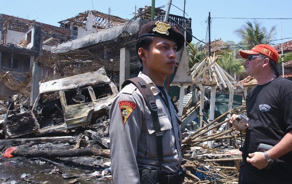 CYK34 - 20021013 - DENPASAR, BALI, INDONESIA : A foreign tourist (R) looks at the destroyed building of what remains of the Padi club the day after a bomb blast in Denpasar, on the Indonesian island o ...