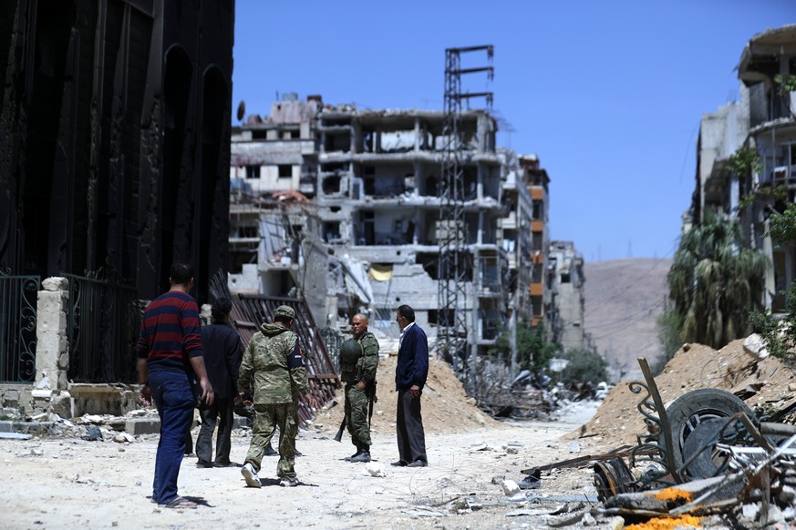 epa06673239 Russian police inspect destruction in Douma city, Eastern Ghouta, the countryside of Damascus, Syria, 16 April 2018. According to media reports, the Syrian army had recently driven the reb ...