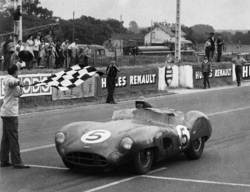 An official doff his hat as he waves the chequered flag as Carroll Shelby of Dallas, Texas crosses the finish line driving an Aston Martin to win the 24 hour race in Le Mans, France on June 21, 1959. ...