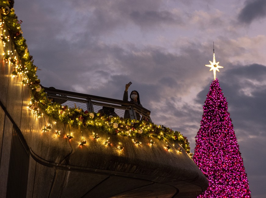 epa10361786 A woman takes a selfie next to a Christmas tree in Hong Kong, China, 12 December 2022. The tree and decorations, set in the West Kowloon Cultural District and Victoria Harbour, are part of ...