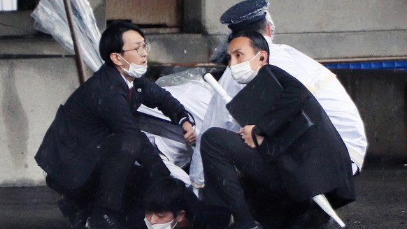 epa10573225 Police officers arrest a man suspected to have thrown explosives as Japanese Prime Minister Fumio Kishida was about to make a stump speech at a fishing port in Wakayama, Wakayama Prefectur ...