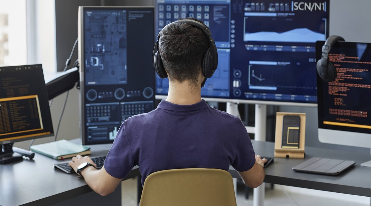 Young IT professional wearing wireless headphones working on computers model released, Symbolfoto property released, KPEF00136