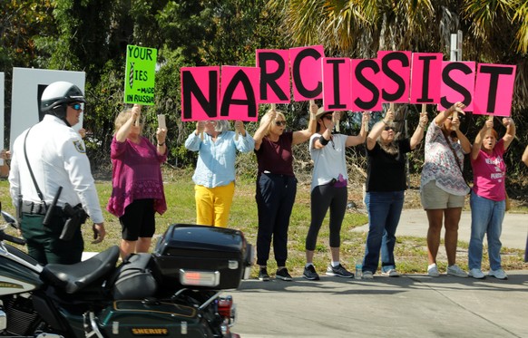 Anti-Trump protesters hold up signs as the motorcade of U.S. President Donald Trump passes by in West Palm Beach, Florida, U.S., March 19, 2017. REUTERS/Kevin Lamarque