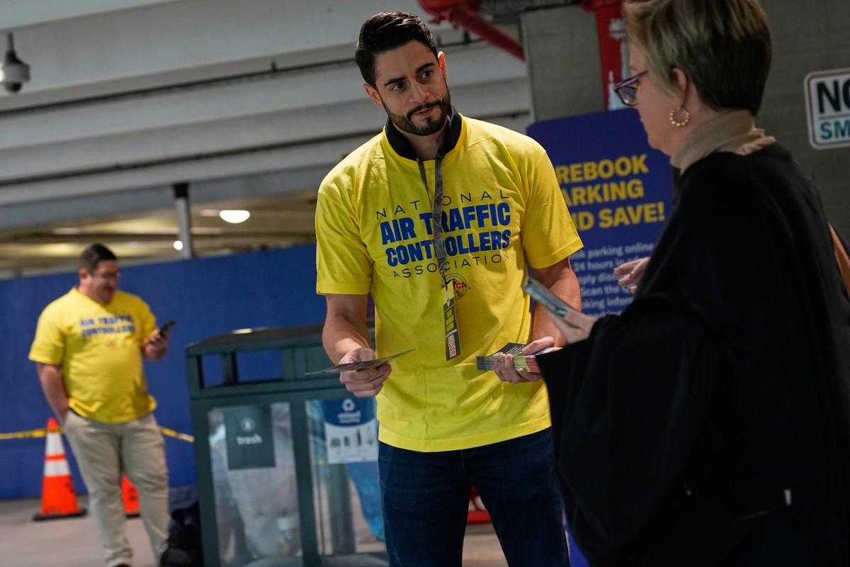 Jose Rodriguez, an air traffic controller, hands out pamphlets urging travelers to contact their representatives to help stop the government shutdown at LaGuardia Airport in New York, Tuesday, Oct. 28 ...