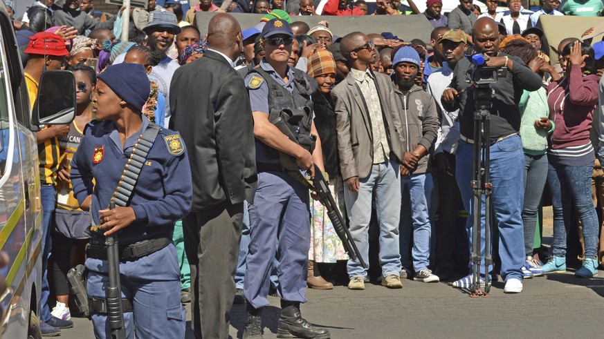 Armed police stand guard outside the magistrates court in Estcourt, South Africa, Monday, Aug.. 21, 2017, where crowds gathered following the brief court appearance of men accused of killing and eatin ...