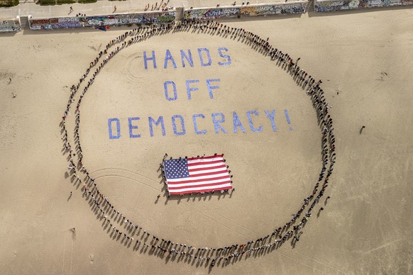 Protesters form a human banner on Ocean Beach during a protest against President Donald Trump, part of the &quot;Hands Off&quot; rallies held nationwide, in San Francisco, Saturday, April 5, 2025. (St ...