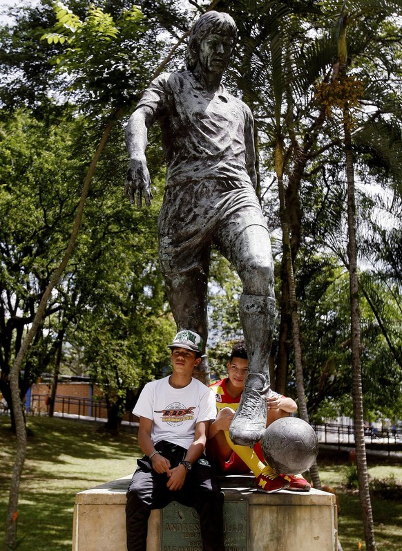 epa04296204 Colombian followers of the late soccer player Andres Escobar pose under the sculpture of Escobar in Medellin, Colombia, on 02 July 2014. Colombians remember Andres Escobar, defender for th ...