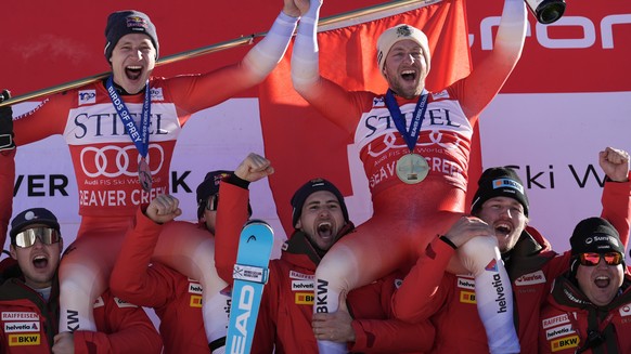 Second place finisher Switzerland's Marco Odermatt, top left, and first place finisher Justin Murisier celebrate with teammates and coach after a men's World Cup downhill skiing race, Friday ...