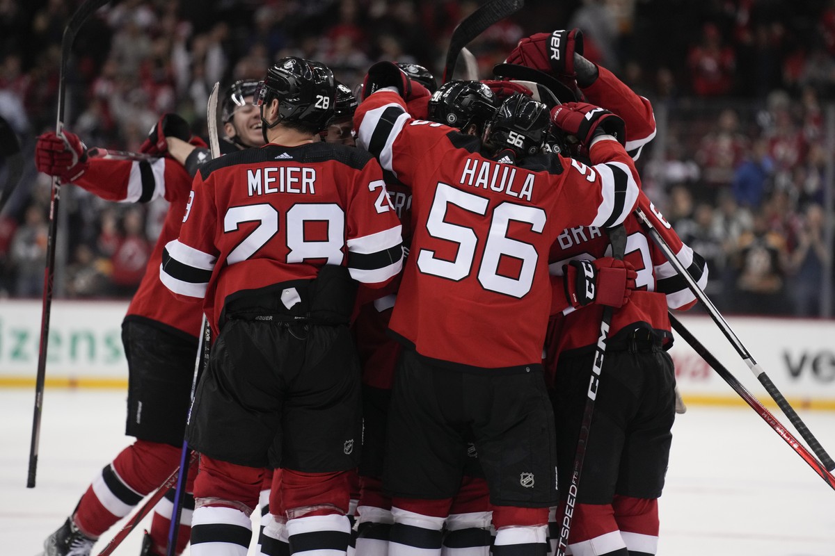 New Jersey Devils players mob Jack Hughes after he scored the game-winning goal during the overtime period of an NHL hockey game against the Boston Bruins in Newark, N.J., Wednesday, Dec. 13, 2023. Th ...