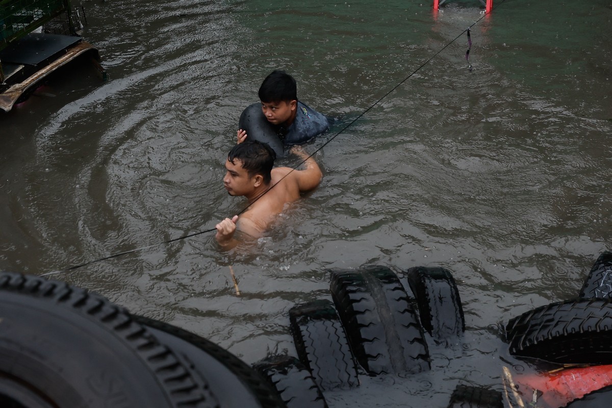 epa11493384 Residents walk in flood following monsoon rainfall in Quezon City, Metro Manila, Philippines, 24 July 2024. Monsoon rains caused by typhoon Gaemi resulted in flooding in Metro Manila and n ...