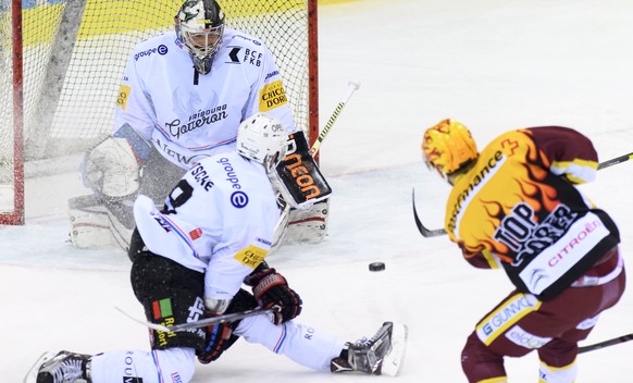 Le joueur fribourgeois, John Fritsche, centre, a la lutte pour le puck avec le joueur Genevois, Nick Spaling, droite, devant le gardien fribourgeois, Benjamin Conz, gauche, lors du match du championna ...