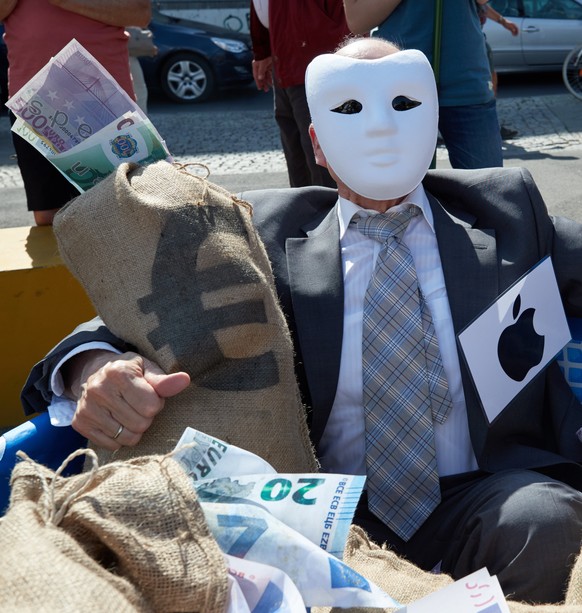 epa06760267 An activist from the nonprofit organization Campact representing Apple hugs a mock bag of money during a street performance in front of the Federal Ministry of Finance building in Berlin,  ...